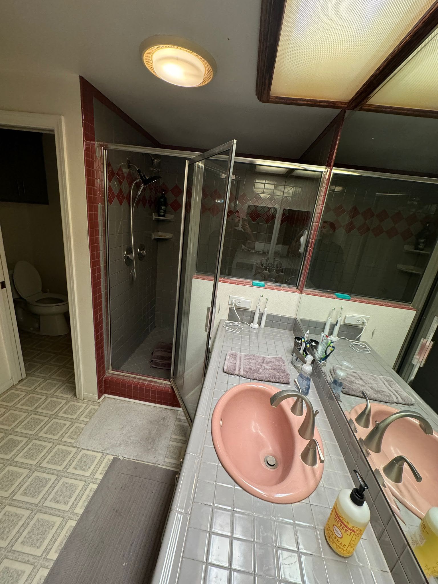 Anaheim master bathroom before the remodel, with a pink sink, red tile, and a dark shower